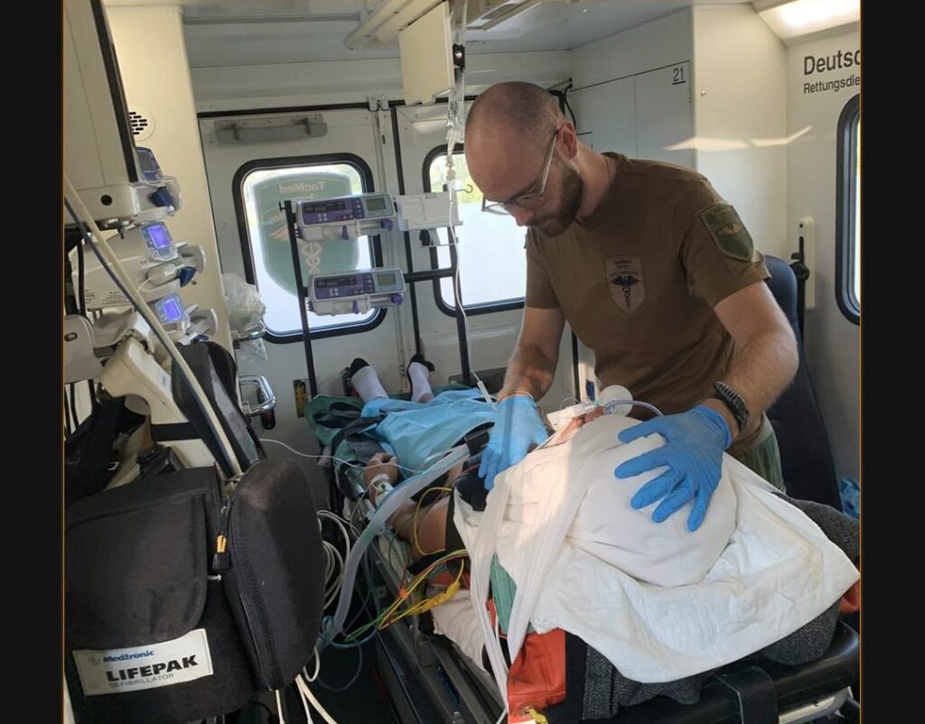 person performing medical attention on a patient in an ambulance