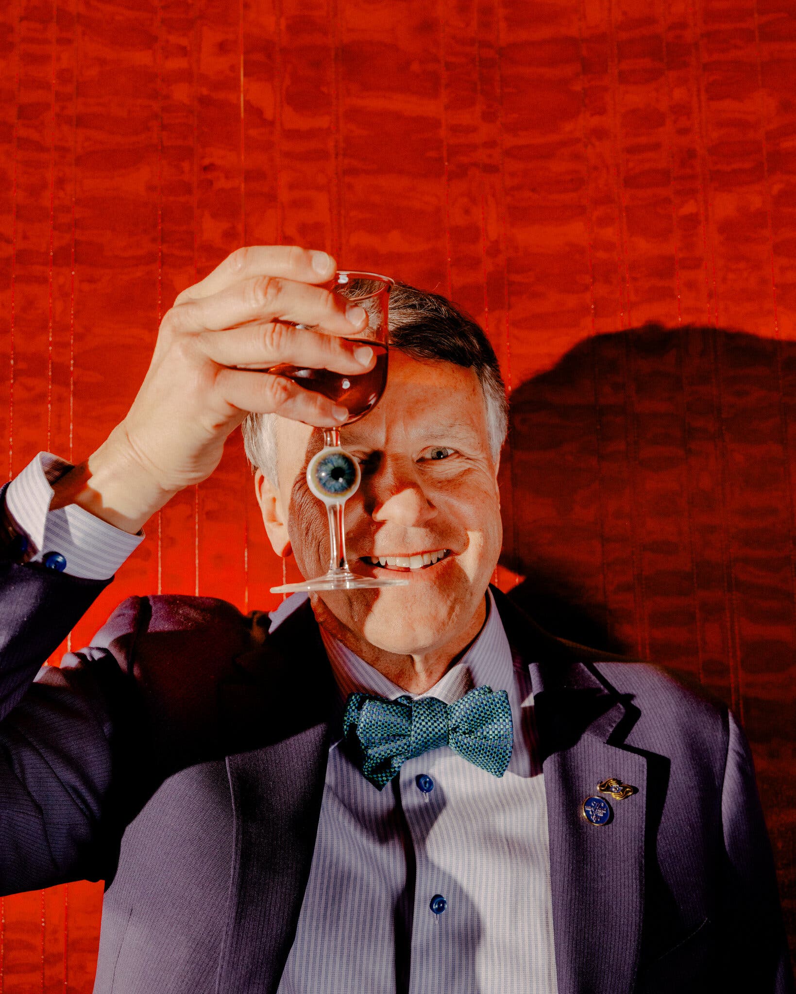 Glen Tullman - white middle aged male - holding a glass with a magical eye over his face