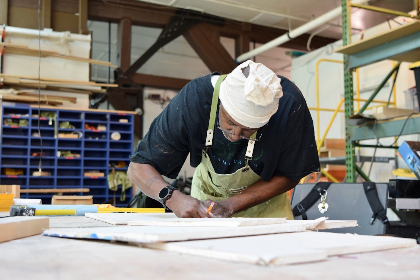man wearing an apron drawing plans working in a tool shop