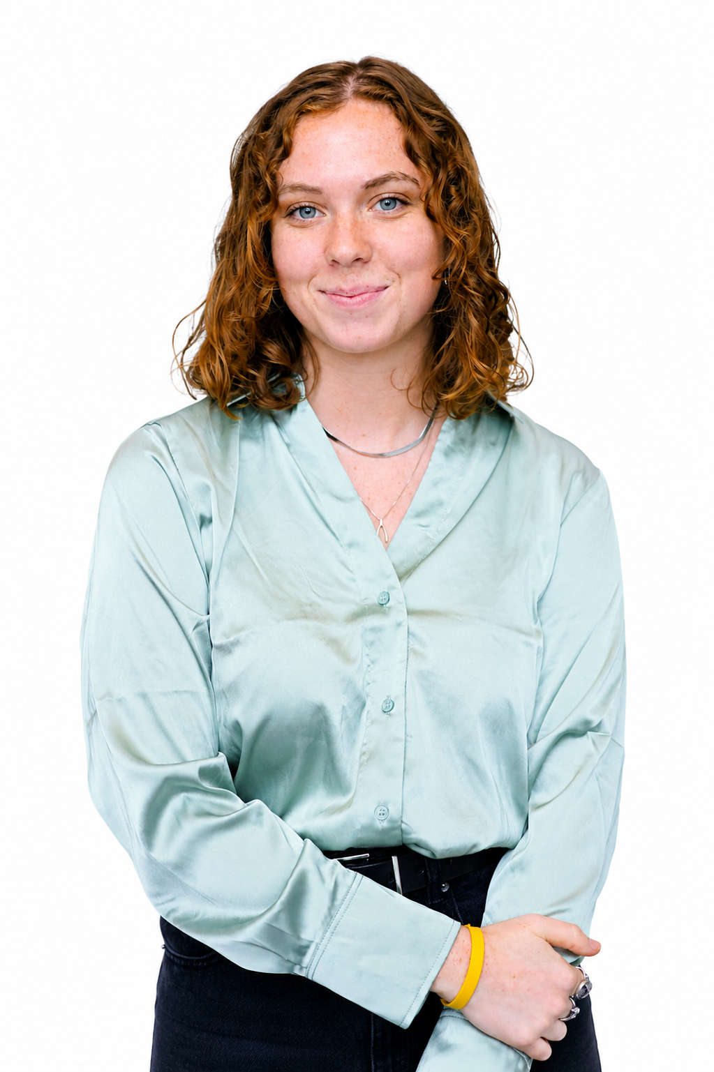 Portrait of a smiling woman with curly red hair in a light blue satin blouse against a white background.
